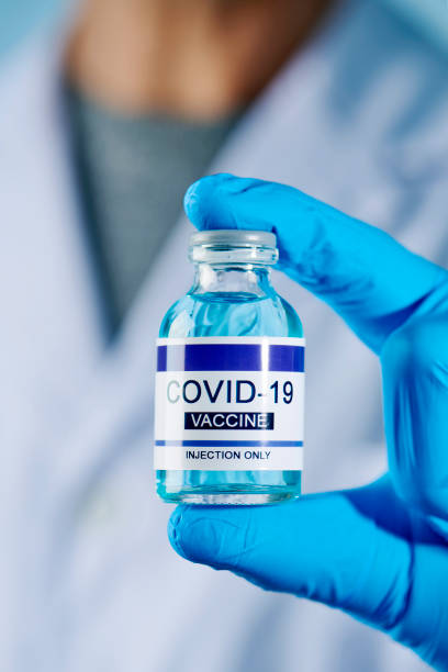 istock man holds a simulated covid-19 vaccine bottle 1306092783