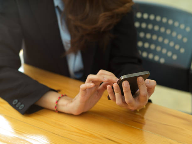 istock Businesswoman hands using smartphone, texting message on wooden table 1306093088
