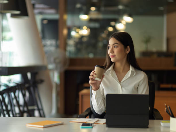 istock Female office worker relaxing with coffee and  looking out through the office window 1306093619