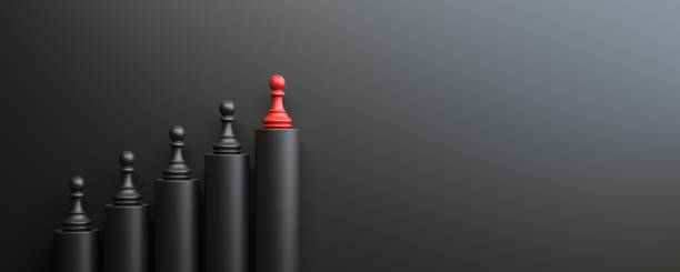 Leadership and growth concept, red pawn of chess, standing out from the crowd of black pawns, on black background with empty copy space on right side stock photo