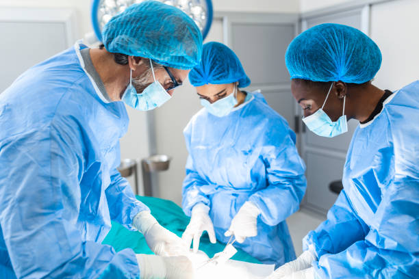 groupe de chirurgiens faisant la chirurgie dans le théâtre d’opération d’hôpital. équipe médicale faisant l’opération critique. groupe de chirurgiens dans la salle d’opération avec l’équipement de chirurgie. formation médicale moderne - opération du coeur photos et images de collection