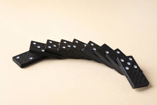 istock Fallen black domino tiles on beige background 1306096469