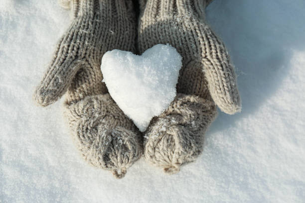 istock Woman holding heart shaped snowball outdoors, top view 1306098984