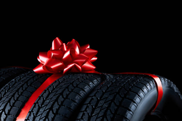 istock Winter tires with red ribbon on black background, closeup 1306099059