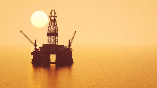 Silhouette of offshore oil rig at sunset.