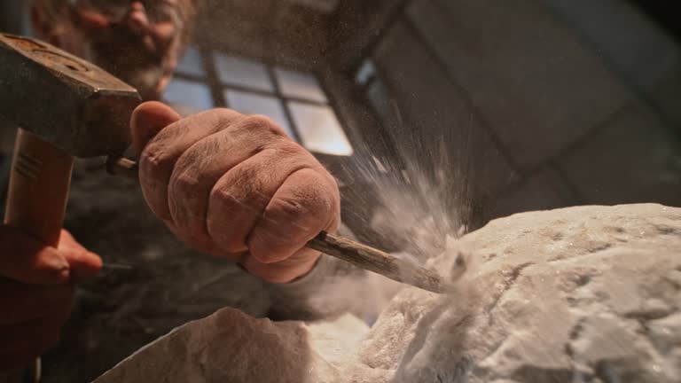 SLO MO DS Stone particles flying into the air as the sculptor chisels the sculpture