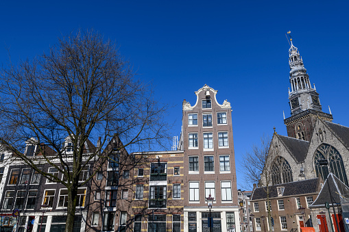 Amsterdam canal houses facades at the Oudeszijds Achterburgwal and the Oude Kerk (Old Church) during a beautiful early springtime day