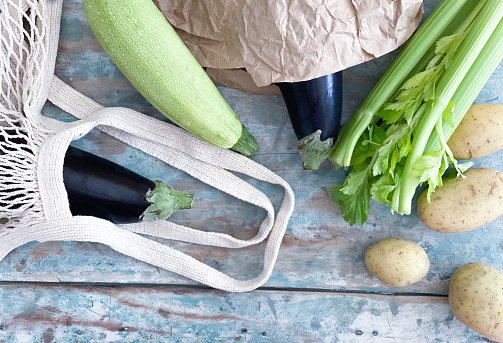 Food backgrounds with vegetables: zucchini, eggplant, celery and potatoes and a reusable mesh bag