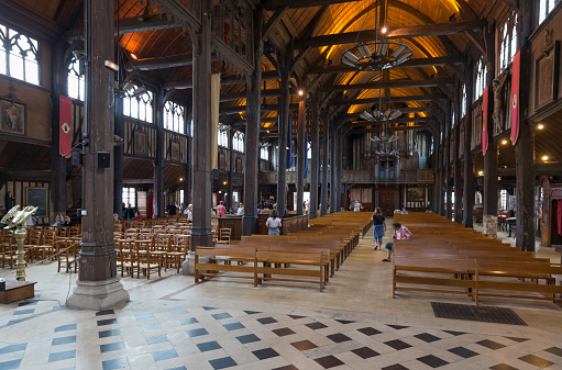 Honfleur, Normandy, France, july 22nd, 2015, tourists sitting and walking around to admire the interior of the Roman Catholic Saint-Catherine's Church in Honfleur, it is the largest wooden church in France and lacks a transept - Catherine of Alexandria was one of the most popular saints of the middle ages, Honfleur has a characteristic old harbour and a rich history - a very popular travel destination