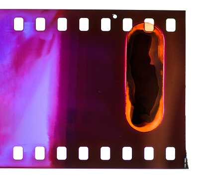 Close-up of the start of a roll of processed 35mm photographic transparency film, showing where the film has been exposed to light.