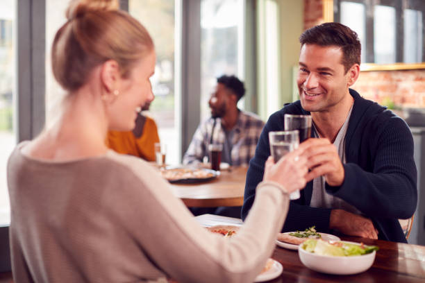 istock Smiling Couple On Date Making Toast Before Enjoying Pizza In Restaurant Together 1306107465