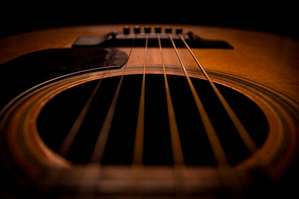 Guitar.Guitar's chords.Acoustic guitar.Music.Music background.Image of an acoustic guitar in the dark.Playing music with some friends in the dark.Classical music.Guitar closeup Closeup image of an acoustic guitar`s chords.The photo was shot in the dark,that is why it shows the guitar so bright.It could be used at any kind of uses such as music background,lyrics background,motivation texts,article about music... chord stock pictures, royalty-free photos & images