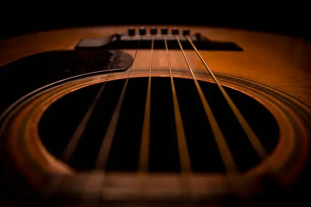 Photo of Guitar.Guitar's chords.Acoustic guitar.Music.Music background.Image of an acoustic guitar in the dark.Playing music with some friends in the dark.Classical music.Guitar closeup