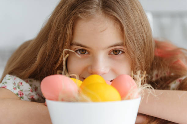 1 ragazza europea carina bianca di 10 anni con uova di pasqua gialle e rosa da vicino - 10 11 years cheerful happiness fun foto e immagini stock