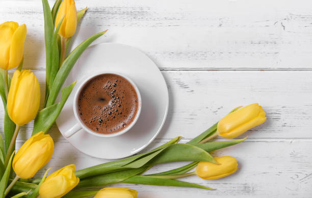 lots of yellow tulips, a cup of black coffee on a white wooden background, gift, flowers, top view - copy space left imagens e fotografias de stock