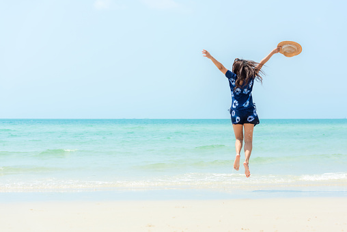 Summer vacations. Lifestyle woman relax and chill on beach background.  Asia happy young people jumping on the wave sea, summer trips walking enjoy  tropical beach. Lifestyle and Travel Concept.
