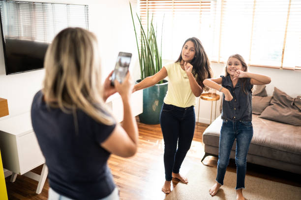 mother filming teenager daughters dancing at home - parent mother music listening imagens e fotografias de stock
