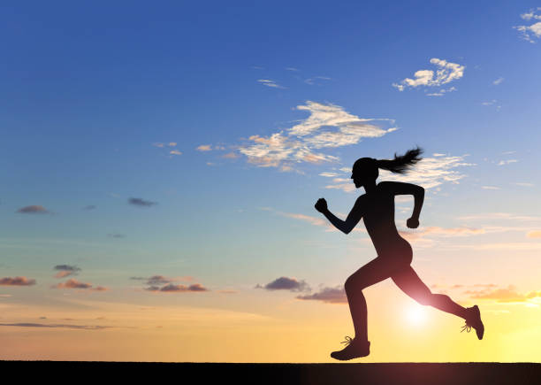 Unrecognizable young woman athlete silhouette at sunset.