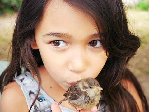 Close-up of a little girl kissing a sparrow