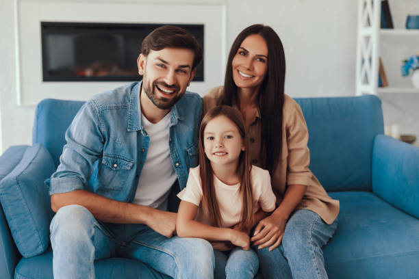 Adorable kid snuggled on a couch with her happy parents