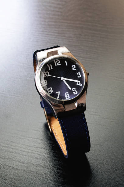 istock Blue wristwatch on a black wooden table 1306120395
