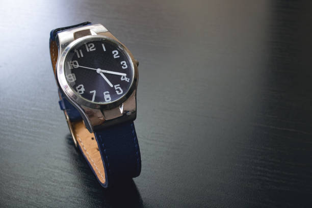 istock Blue wristwatch on a black wooden table 1306120402