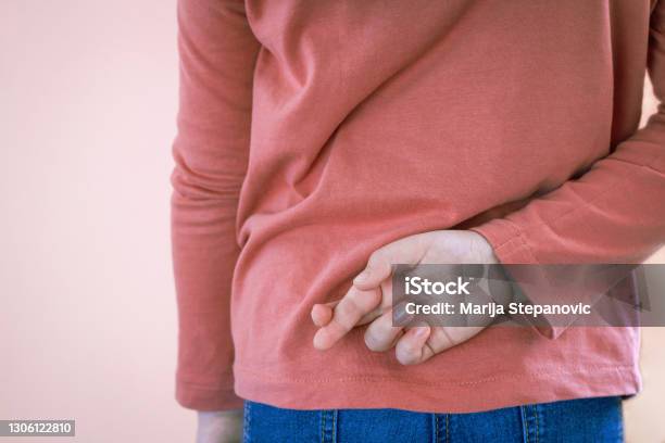 Lying Concept With Girl Child Crossing Her Finger Behind Back On Light Background With Copy Space April Fools Day Stock Photo - Download Image Now