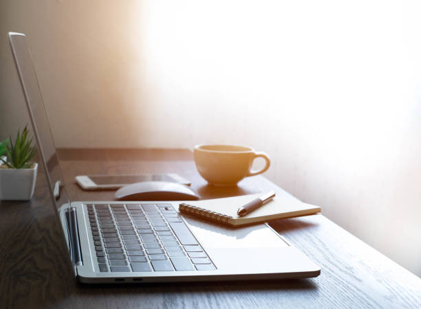 istock soft focus of Office desk table with keyboard of laptop computer, coffee cup and notebook, glasses. Business and finance concept. Workplace with morning sunlight from window with copy space. 1306123915