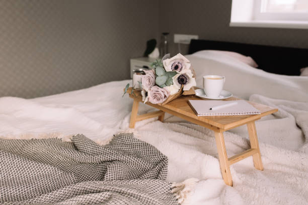 istock Coffee table on bed. Flowers, cup, note pad, pen. Interior gray interior, plaid 1306124435
