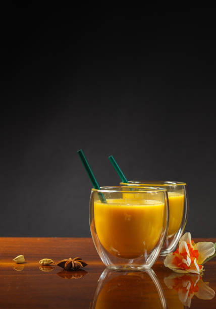Two thermal glasses with golden milk, on a black background, close-up. Hot drink with spices. Vertically with space stock photo