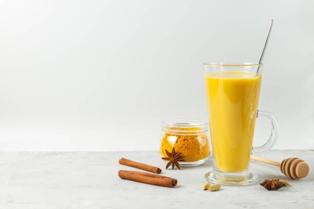 Golden moon milk with turmeric in a tall glass on a light background, spiced latte. Close-up with space. stock photo