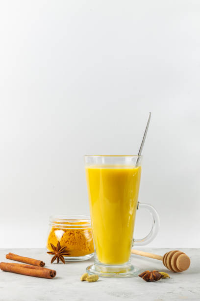Golden milk with turmeric and honey in a tall glass. Spiced latte, vertical with space. stock photo