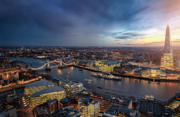 The illuminated skyline of London along the river Thames dusring dusk The illuminated skyline of London along the river Thames with Tower Bridge and the modern office skyscrapers during dusk, United Kingdom central london skyline stock pictures, royalty-free photos & images