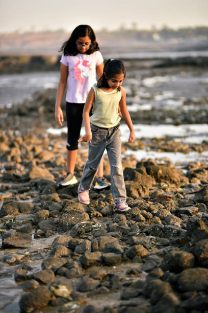 istock Two girls walking on the rocks on beach 1306129269