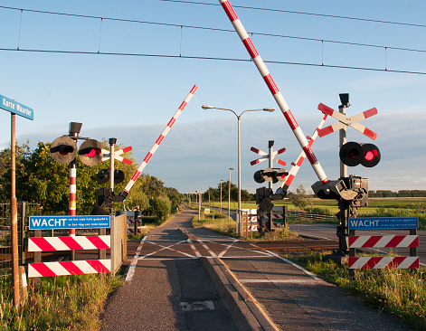 A railroad crossing while a train is nearing. The barriers are closing