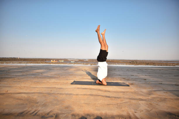 istock Man doing headstand yoga position on the beach 1306129735