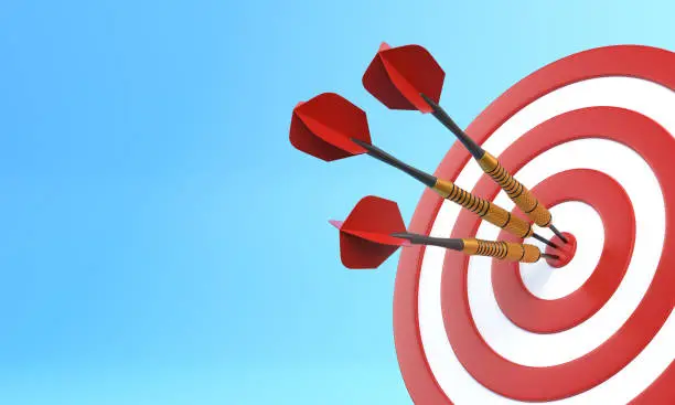 Photo of Three darts hitting a red target on the center on blue background with copy space