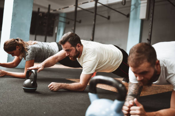 istock Athletes Performing Perfect Form Kettlebell Plank In Gym 1306136555