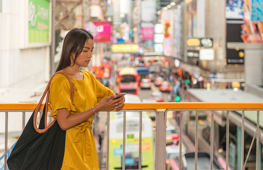 A woman pausing to check her phone on her commute home through Hong Kong's Mong Kok district.