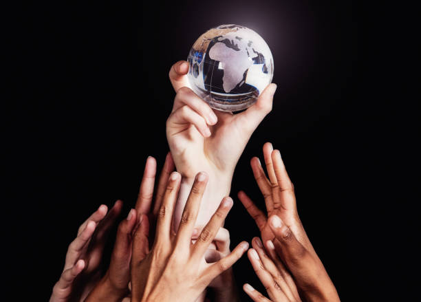 groupe de nombreuses mains diverses tend la main pour un globe de cristal du monde, l’afrique face à la caméra - human hand reaching black white photos et images de collection