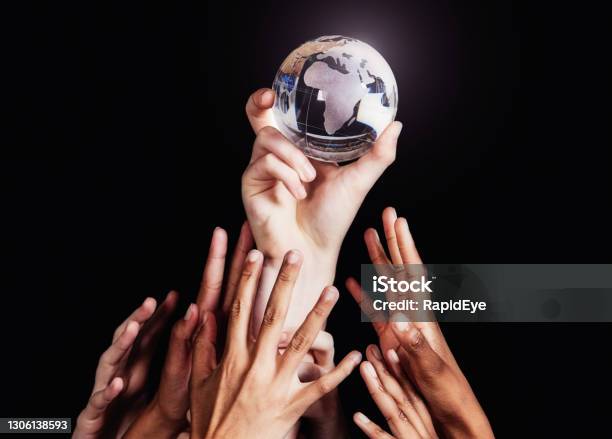 Group Of Many Diverse Hands Reaches Up For A Crystal Globe Of The World Africa Facing The Camera Stock Photo - Download Image Now