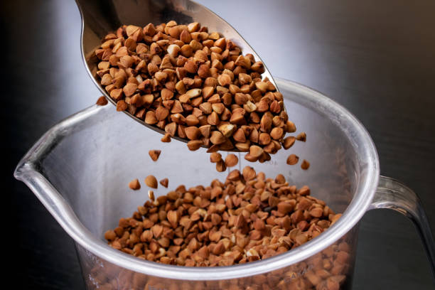 istock Buckwheat groats in a spoon on black background 1306140193