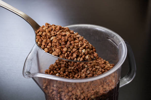 istock Buckwheat groats in a spoon on black background 1306140292