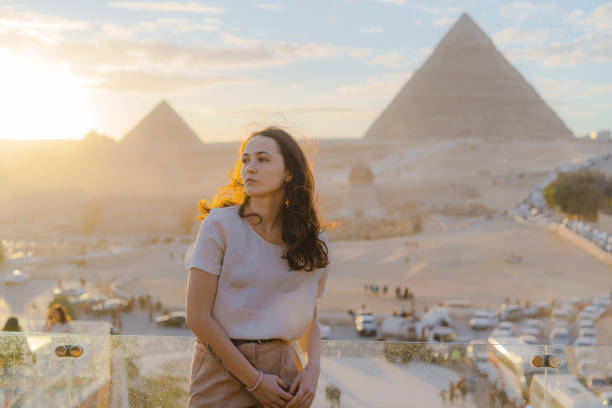 женщина, стоящая на террасе на фоне пирамид гизы - tourist egypt pyramid pyramid shape стоковые фото и изображения