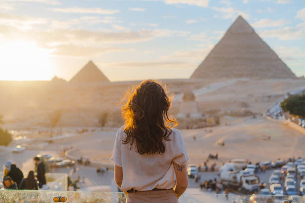 frau steht auf der terrasse im hintergrund der pyramiden von gizeh - travel locations stock-fotos und bilder