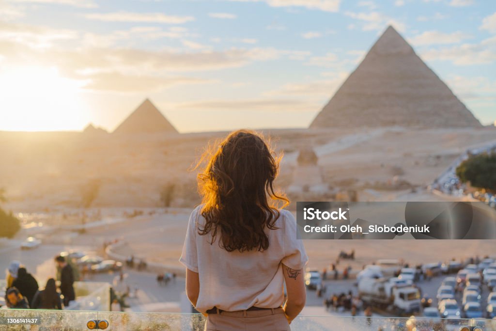 Woman standing on the  terrace on the  background of Giza pyramids Young Caucasian woman standing on the  terrace on the  background of Giza pyramids Travel Stock Photo