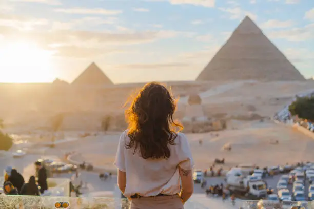 Young Caucasian woman standing on the  terrace on the  background of Giza pyramids