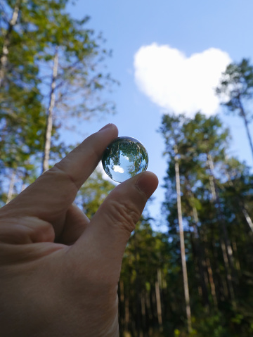 A heart shaped cloud reflected in a crystal marble indicating a sustainable bright future.