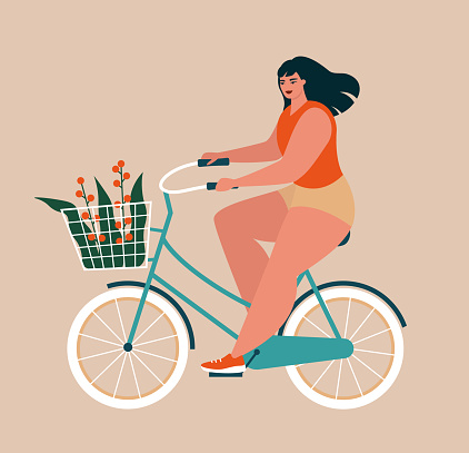 Body positive woman. Beautiful stylish young girl riding a bicycle with a bouquet of flowers in a basket. Healthy active lifestyle, summer concept. Plus size lady keeping fit.