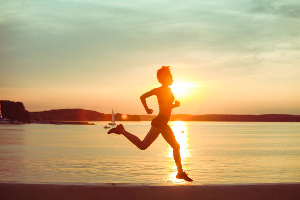 日没時に走るアフリカの女の子のアスリート - running jogging african descent nature ストックフォトと画像